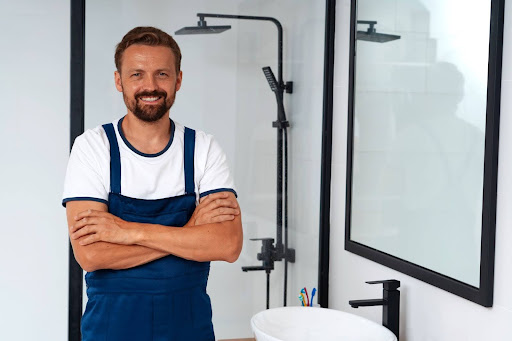 plumber smiling at camera with arms crossed standing in bathroom